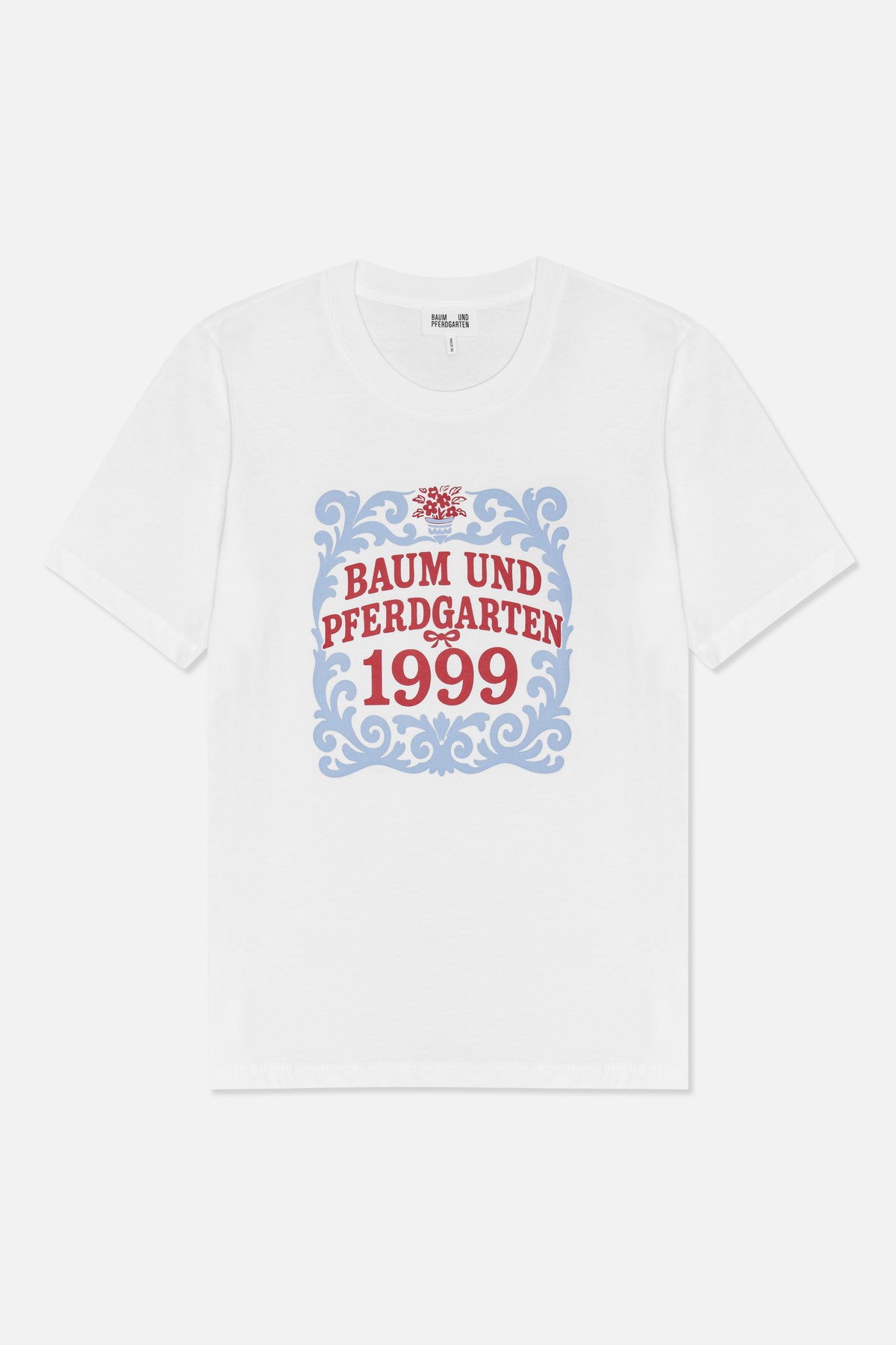 Framifrån: en vit kortärmad t-shirt med en blå dekorativ ram, en röd blomdetalj och texten 'Baum und Pferdgarten 1999'.