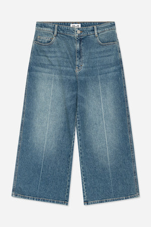 Framifrån: blåtvättade jeans med orangea sömmar, hällor, gylf med knappar och rundade framfickor.