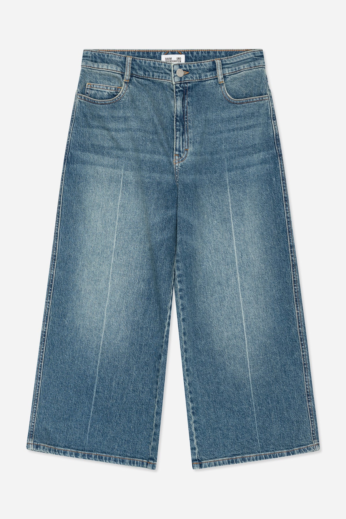Framifrån: blåtvättade jeans med orangea sömmar, hällor, gylf med knappar och rundade framfickor.