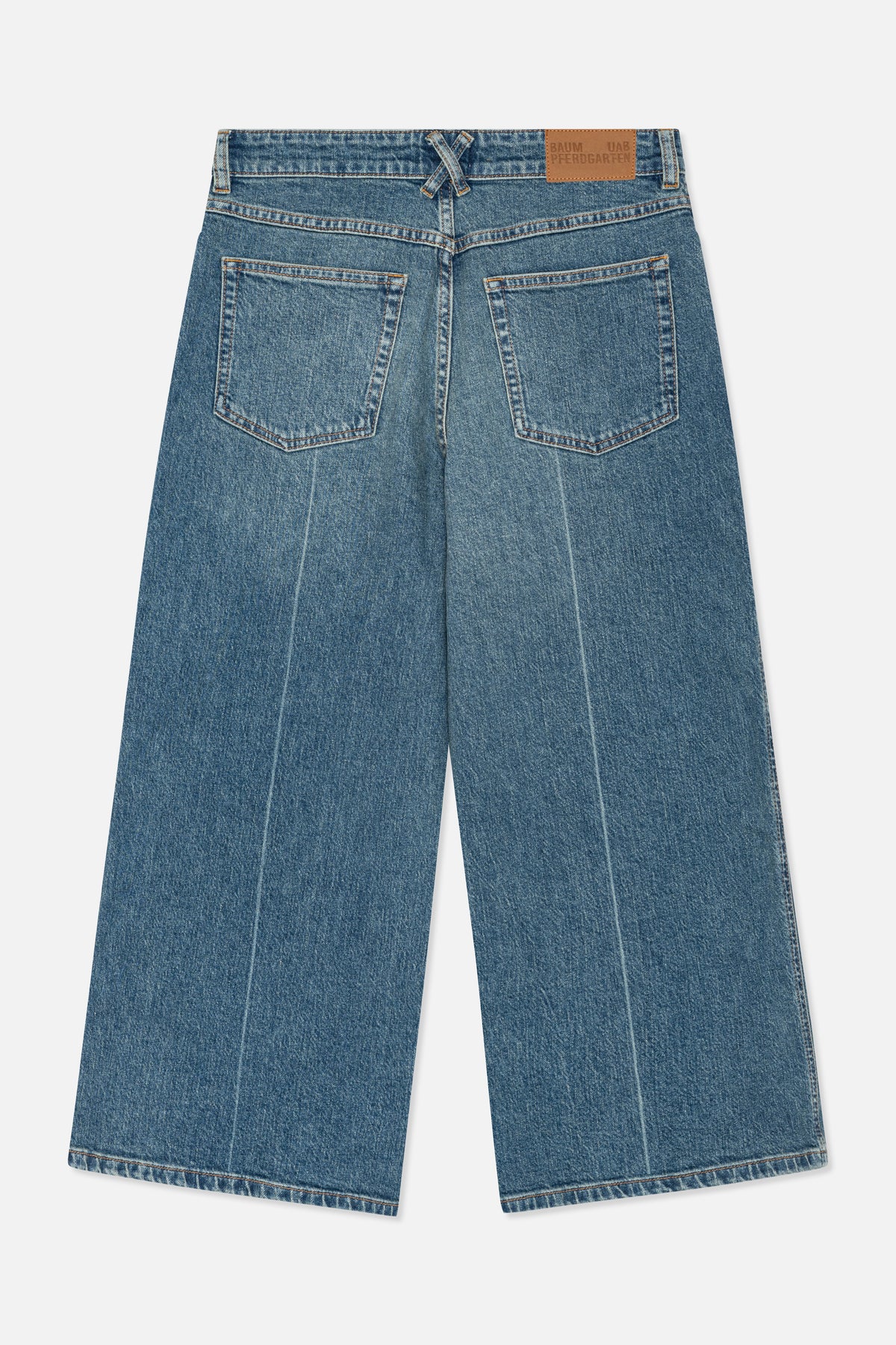 Närbild på baksidan av blåtvättade jeans med två påsydda bakfickor, orange kontrastsömmar och en ljusbrun märkespatch i midjebandet.