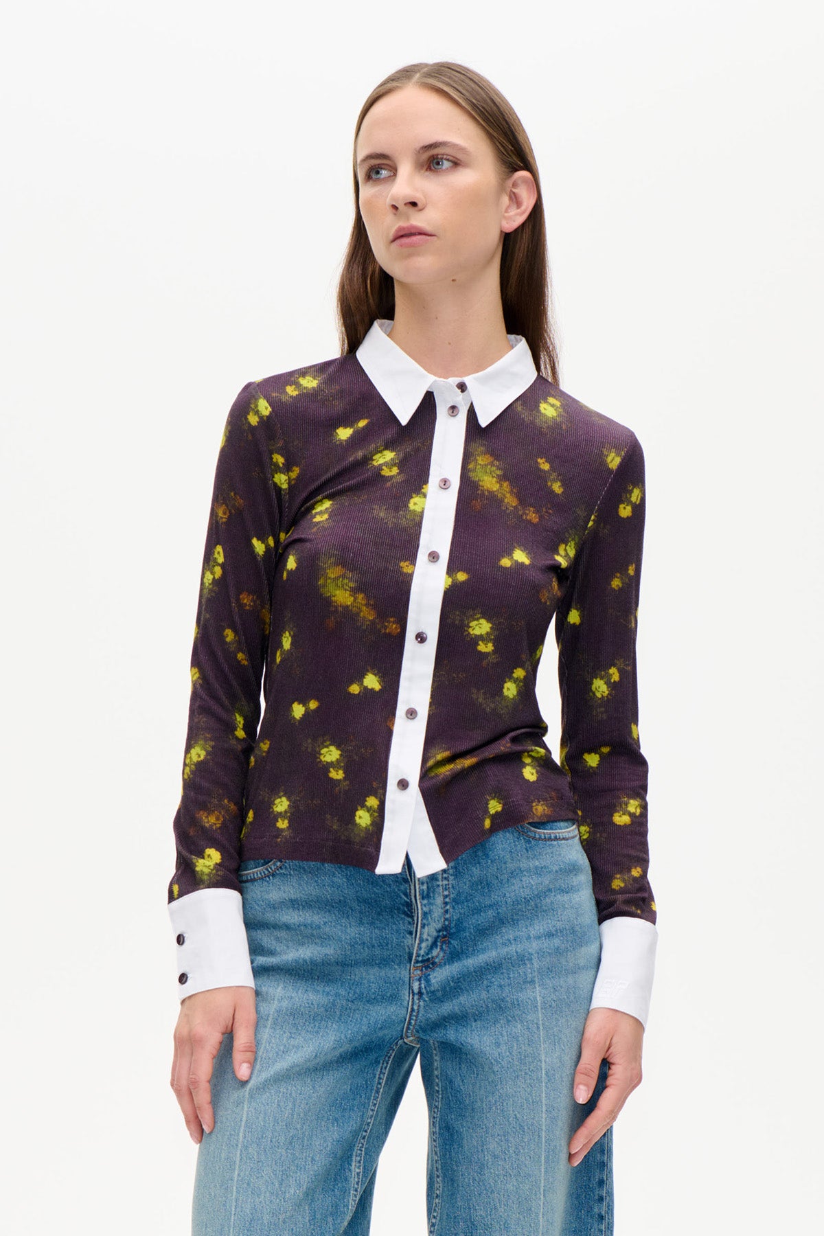 Framifrån: mörk plommonfärgad blommig knäppkofta med klara gulgröna blommor, vit krage och vita muddar, stylad med blå jeans.