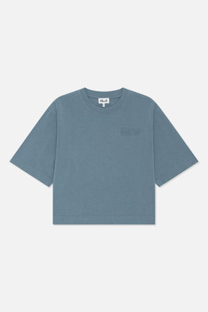 Framifrån en blågrå kortärmad t-shirt med rund halsringning och en diskret ton-i-ton Baum und Pferdgarten-logga på bröstet.