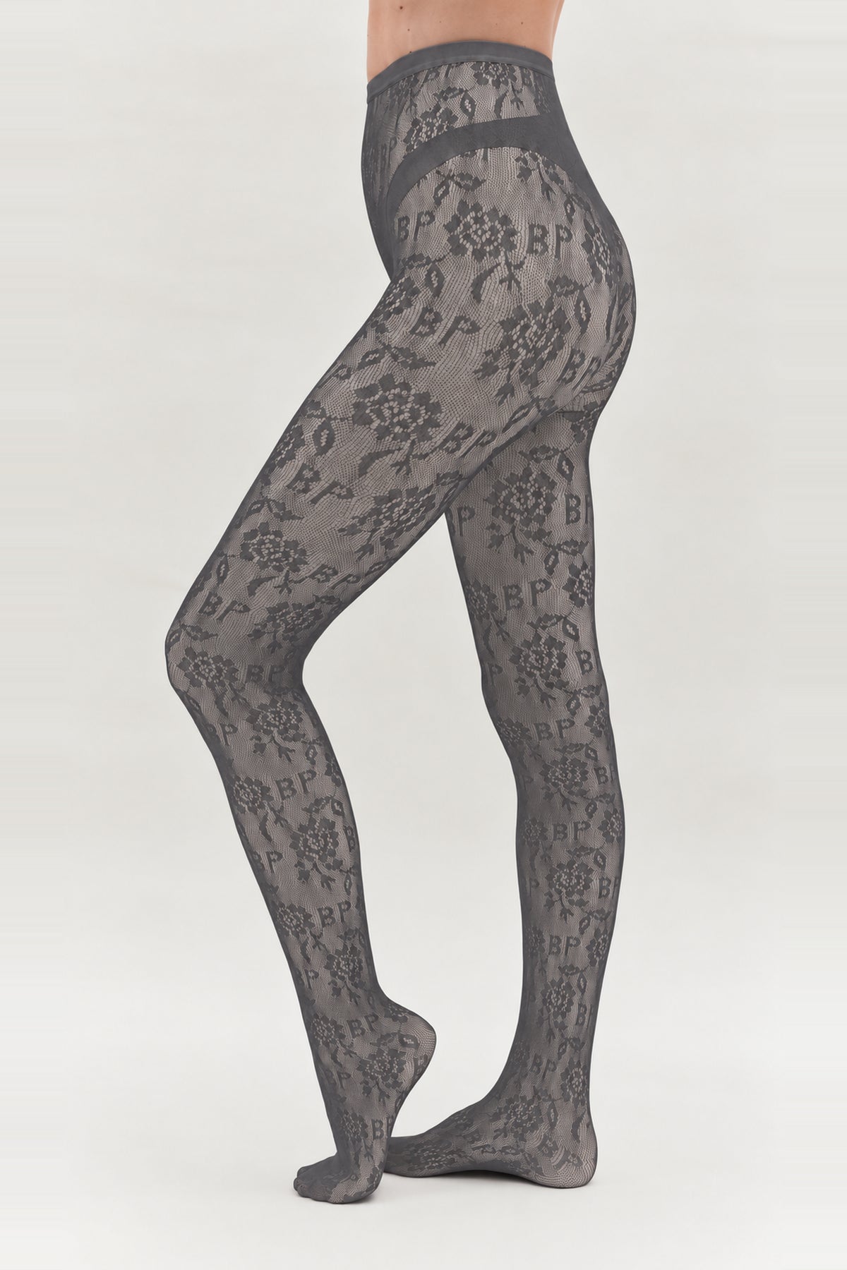 Sheer charcoal-grey tights with an all-over floral and BP monogram pattern, shown on a model from waist to feet.
